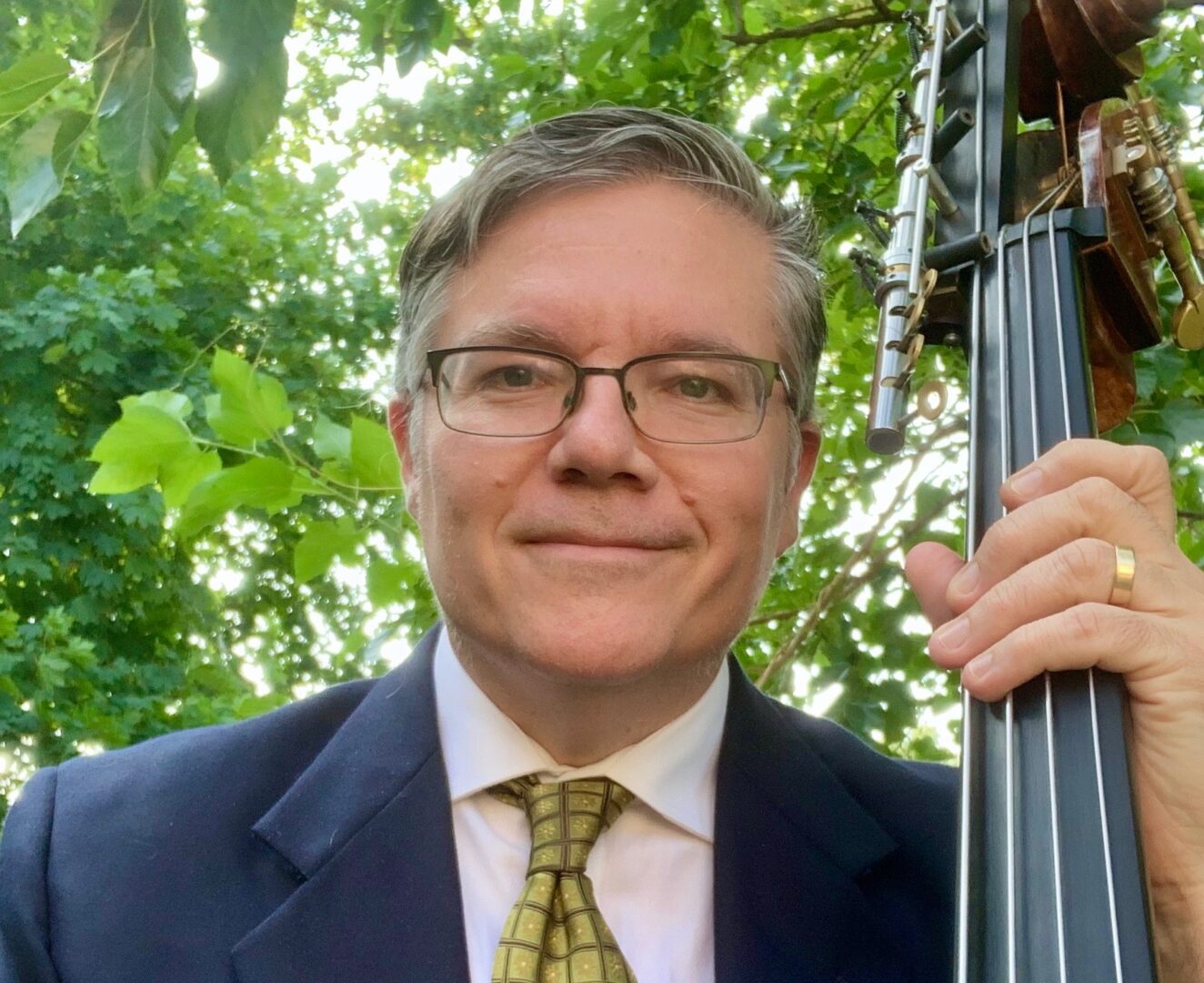 A man in suit and tie holding a bass.