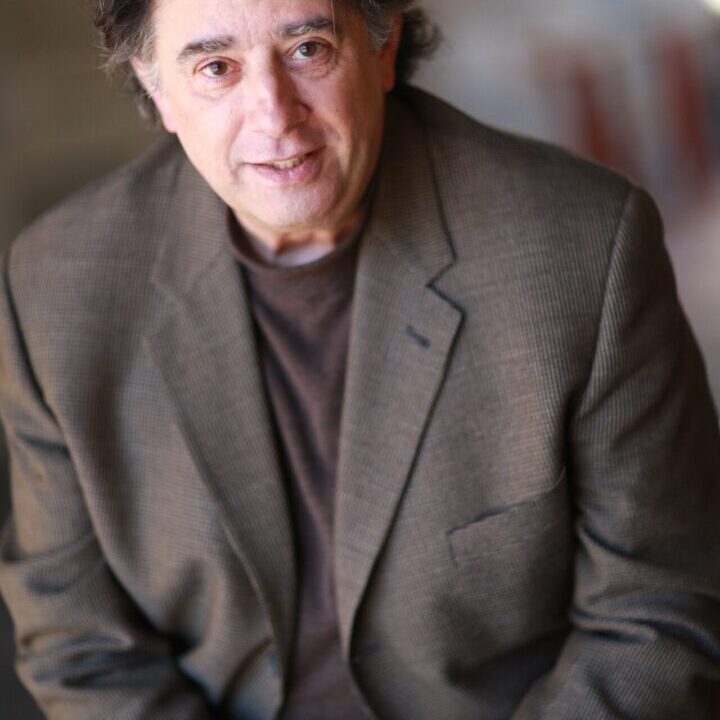 A man in a suit and glasses is posing for the camera.